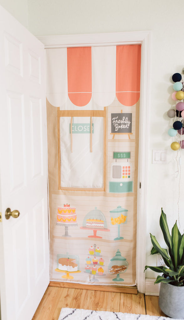 Bakery inspired creative play playhouse storefront that hangs  in  the doorway.  Roll up window to spark open ended play. Creative kid's playroom design ideas